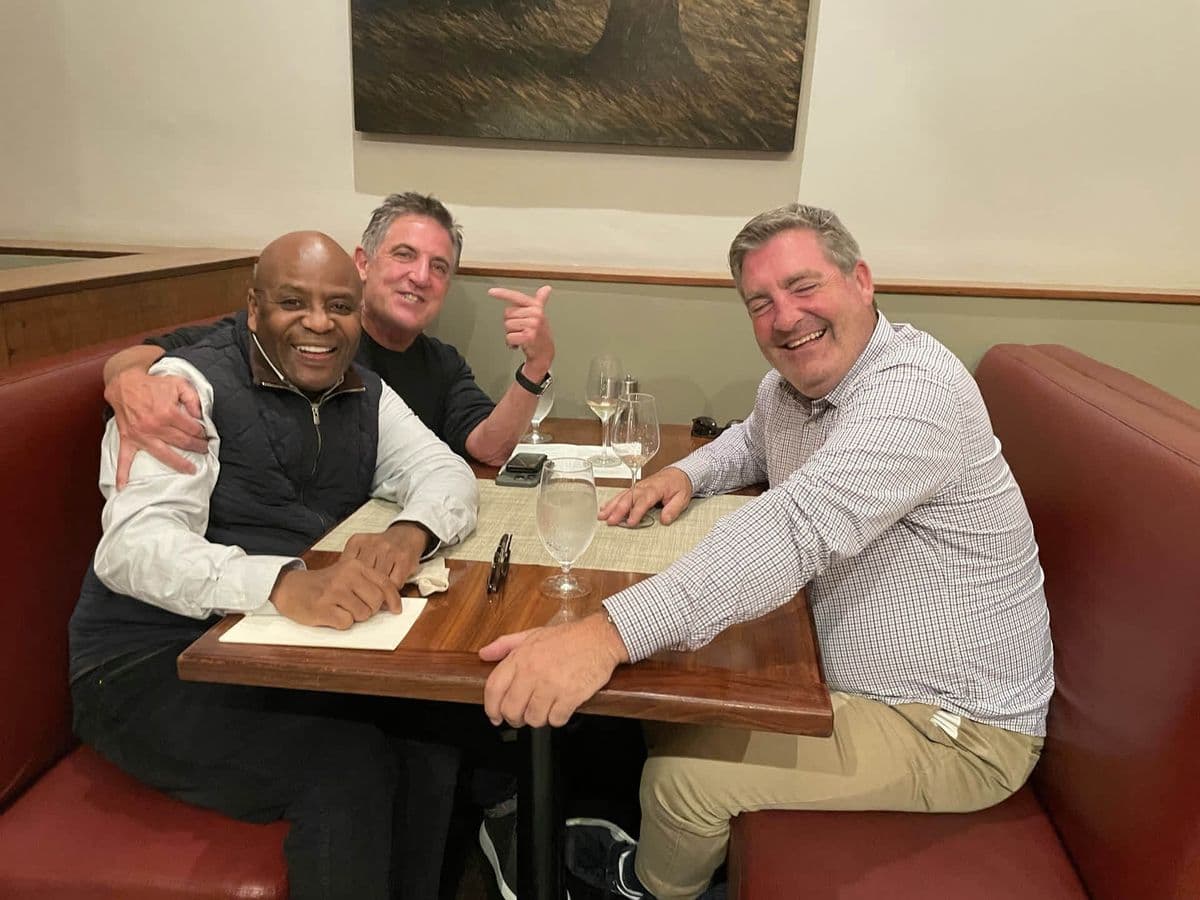 Alex with two friends laughing at a restaurant booth
