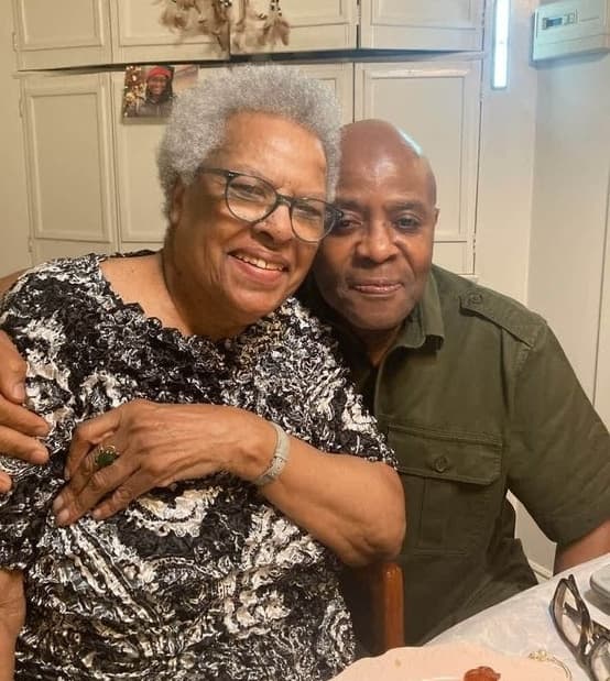 Alex embracing an older woman at a dinner table