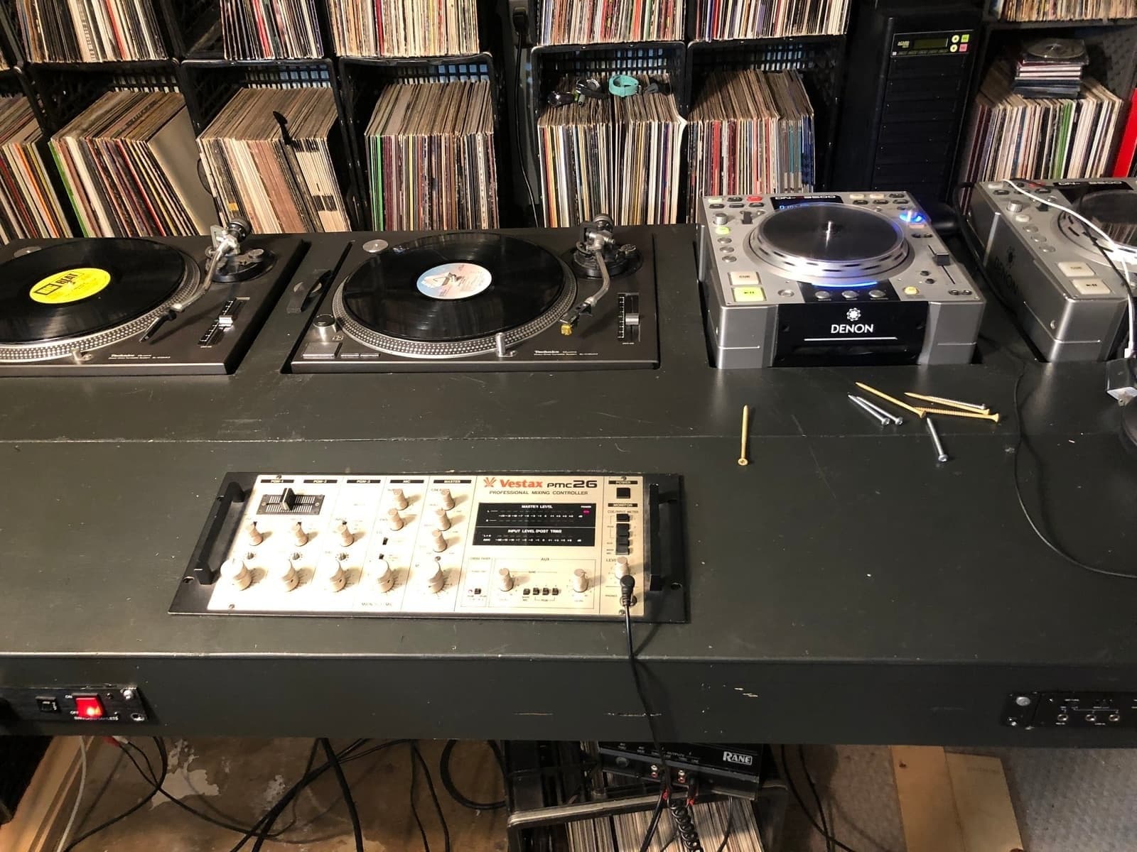 DJ Afrique's home studio with dual turntables, Vestax mixer, and walls of vinyl